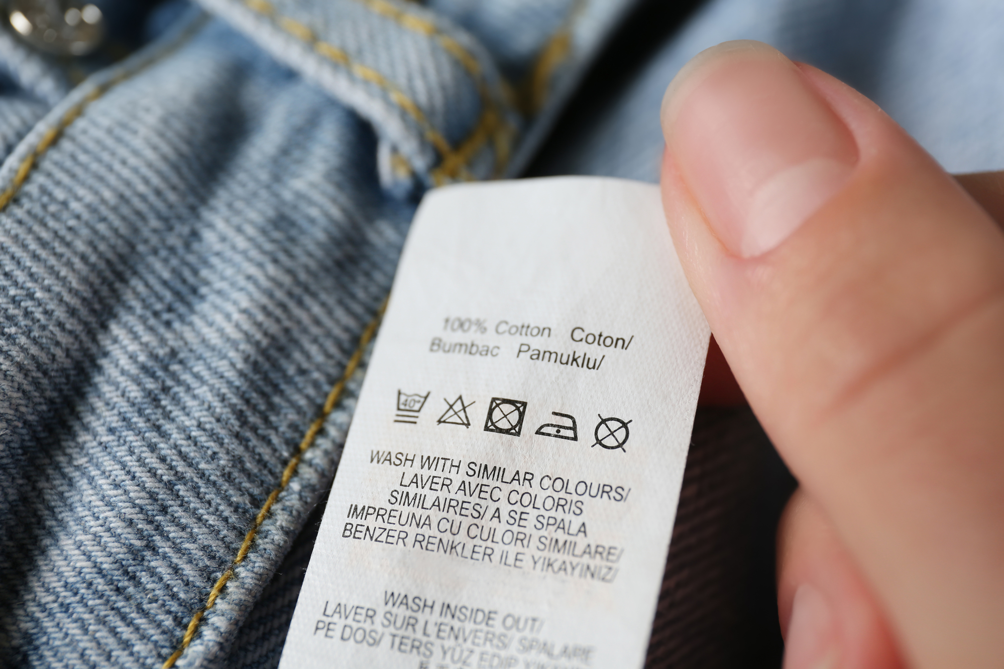 Woman reading clothing label with care symbols and material content on jeans.jpg