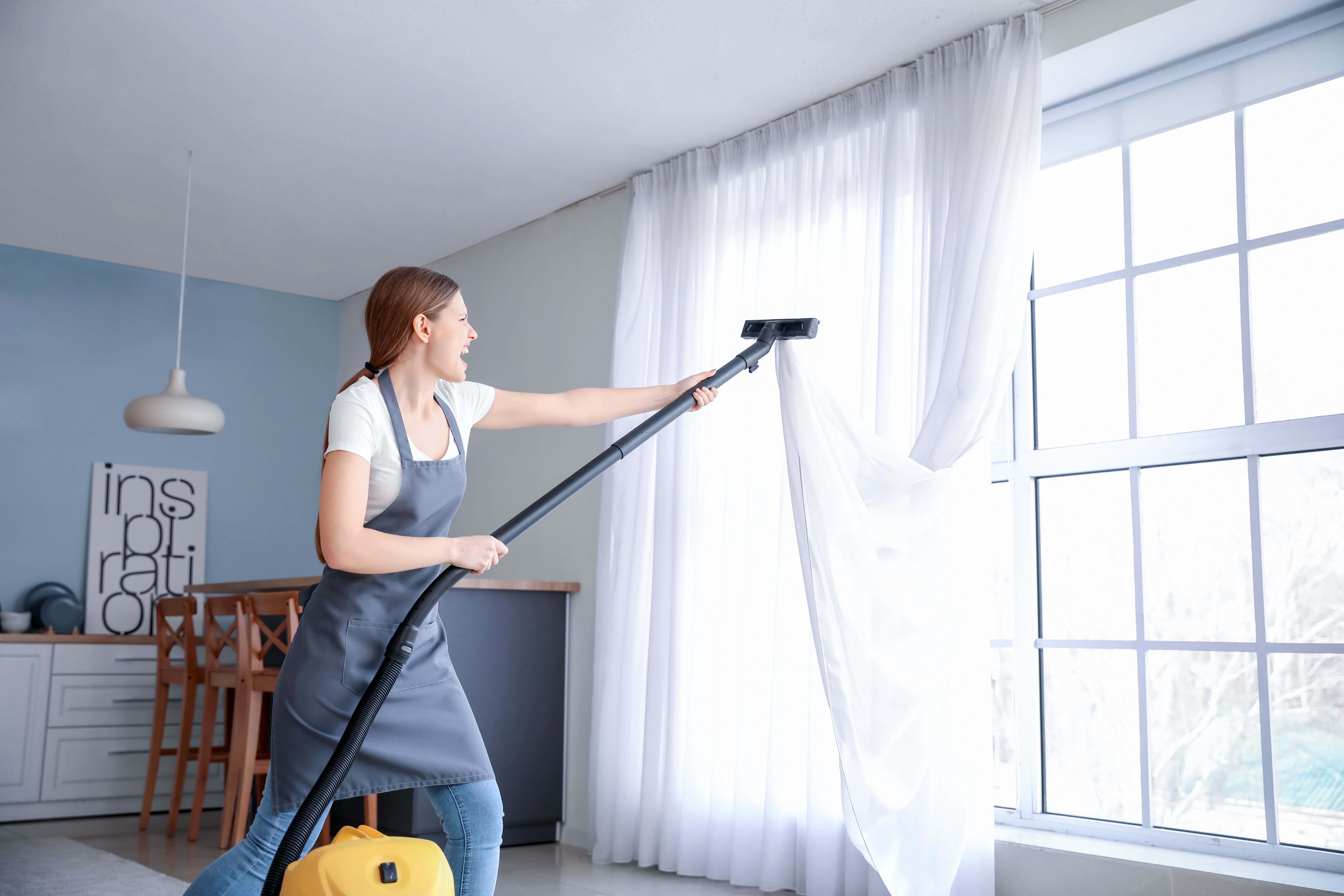 Woman vacuuming cleanin white curtains.jpg